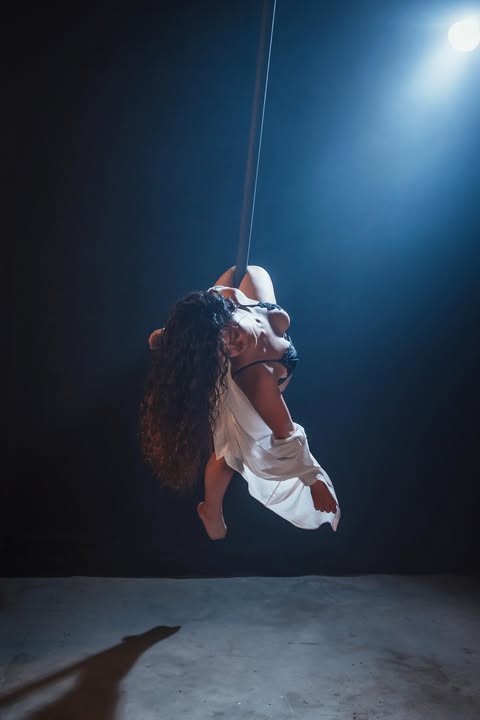 Chloé en performance Flying Pole en tenue blanche sous éclairage bleu